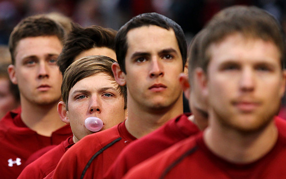 A South Carolina baseball player blows a bubble of gum while standing with teammates as the national anthem is performed.